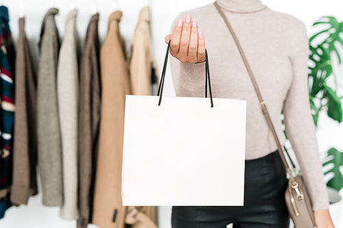 Young stylish female shopper with handbag standing in front of camera while spending time and money in boutique