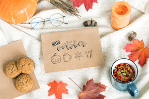 October background with autumn leaves, food and drink, acorns, candle and eyeglasses on towel