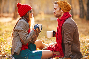 Stylish couple with tea-cups talking in park