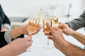 Hands of young friends holding flutes of sparkling of champagne and clinking with them while making toast for holiday at party