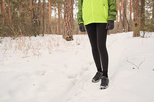 Close-up of unrecognizable woman in sport shoes hiking in winter forest