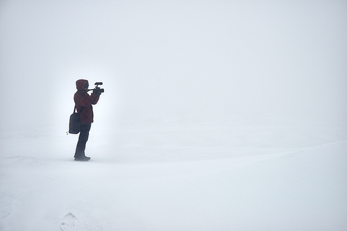 Lonely photographer shooting in winter field