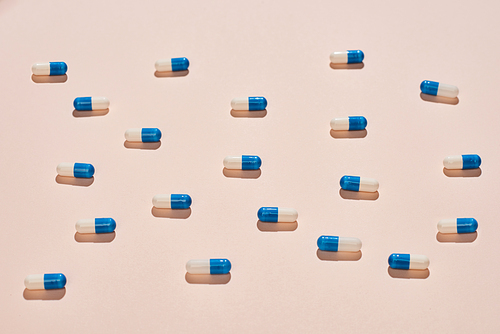 White and blue capsules on neutral pale pink background horizontal flat lay pattern shot