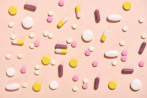 Various colourful pills on neutral pale pink background horizontal flat lay pattern shot