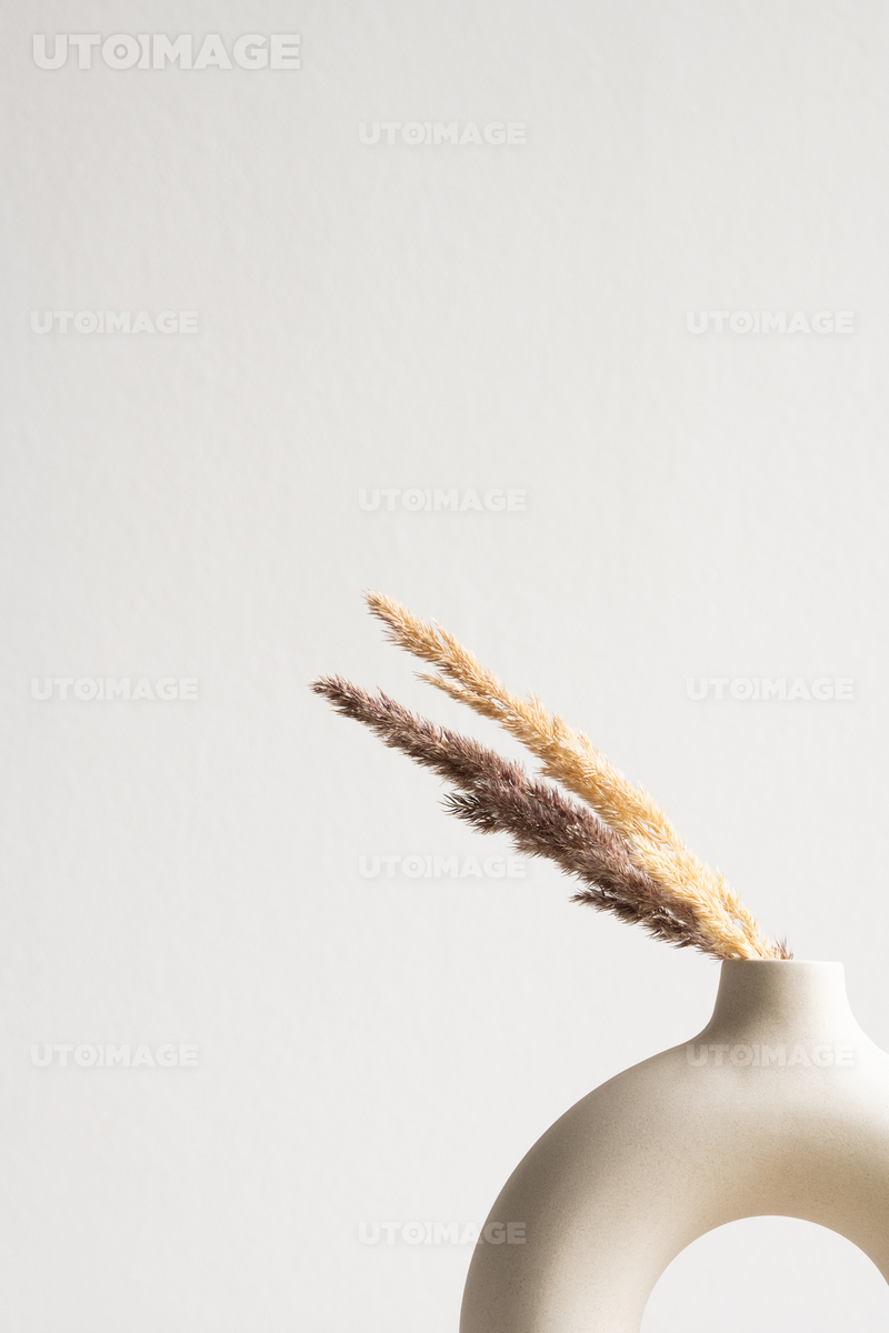 Dried wildflowers in grey clay or ceramic vase standing on table