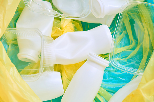 Empty plastic bottles and containers in yellow plastic garbage bag, horizontal flat lay close up shot