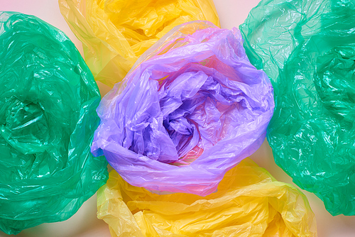 Horizontal from above flat lay shot of empty multi-coloured plastic garbage bags on neutral background