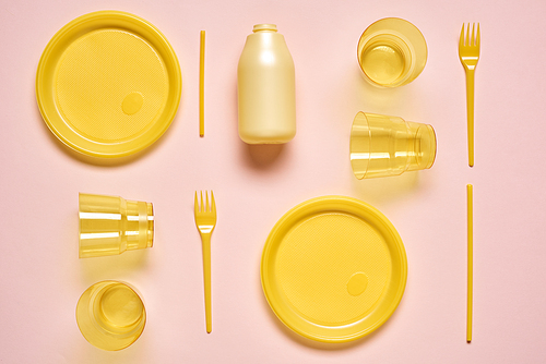 Yellow plastic utensil on pale pink background, horizontal from above flat lay shot