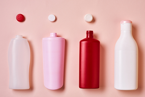 Horizontal from above flat lay conceptual image of plastic bottles with tops on pale pink background