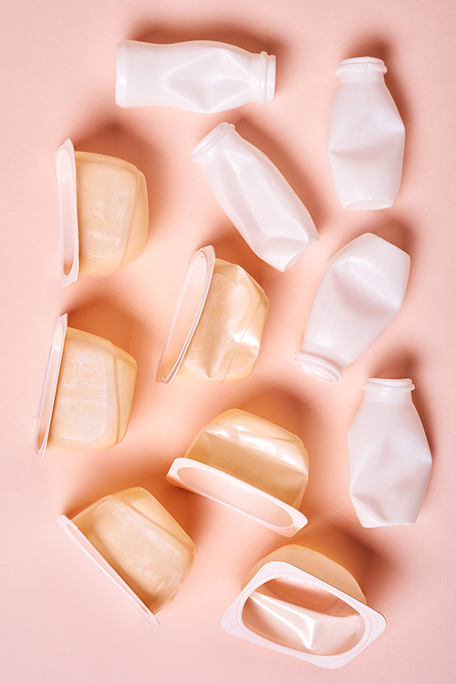 Vertical from above flat lay conceptual image of plastic bottles with tops on pale pink background