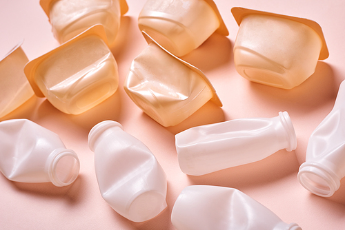 Horizontal high angle conceptual shot of plastic bottles with tops on pale pink background