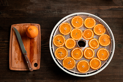 Group of fresh orange slices and halves of the fruits on wooden chopping board on the kitchen table cut by housewife for eating