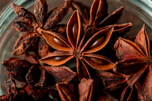 Macro shot of dry star anise of brown color in glass bowl that is used for making mulled wine or seasoning desserts and candied fruits