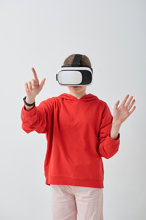 School girl in red hoodie using virtual reality simulator while solving task in educational video game