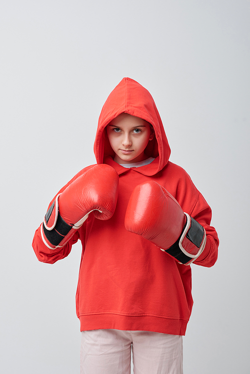 Serious teenage girl in hoodie looking with anger at camera and ready for boxing
