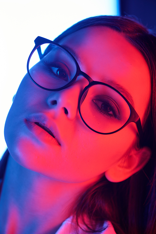 Close-up of sexy attractive girl in glasses posing in neon pink and blue light