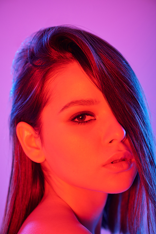 Portrait of seductive woman with hair on half of face posing with open mouth in neon color