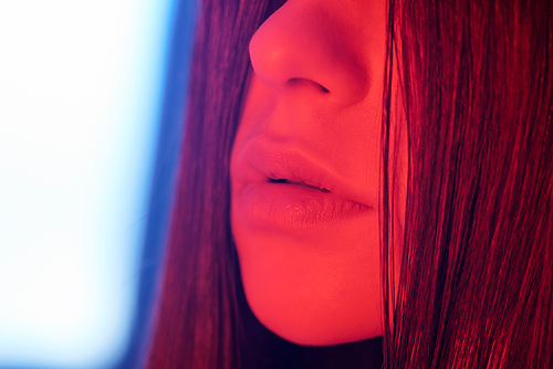 Close-up of seductive lips of brunette woman in neon light, temptation concept