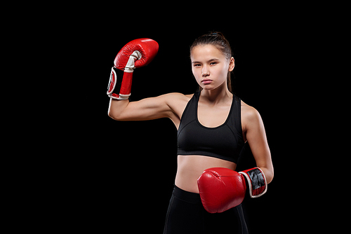 Young strong sportswoman showing her power before training or competition while standing in front of camera