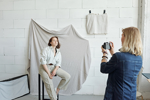 Professional photographer with blond hair working with model in photo studio