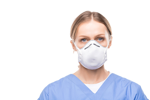 Portrait of attractive young nurse in respiratory mask and scrubs standing against white background