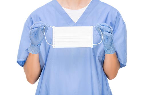 Unrecognizable surgeon in scrubs and surgical gloves holding face mask and standing against white background, protection concept