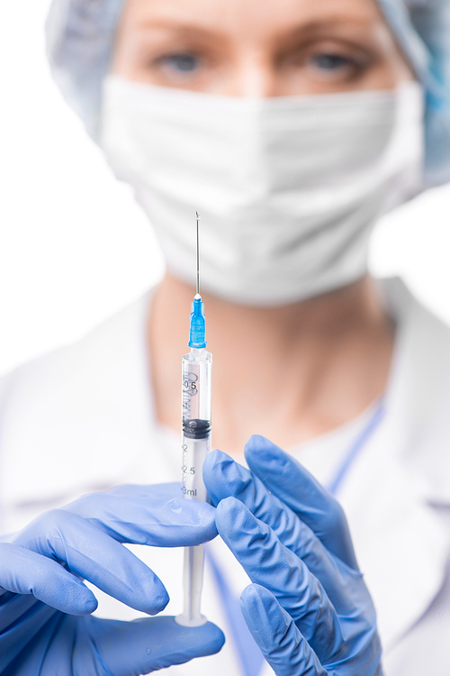 Close-up of female doctor in surgical gloves holding syringe while preparing to make injection