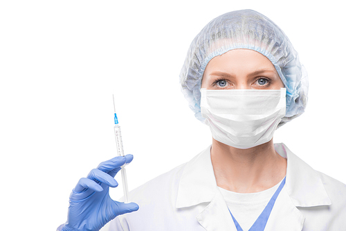 Portrait of female doctor in face mask and surgical cap holding syringe of vaccine against white background