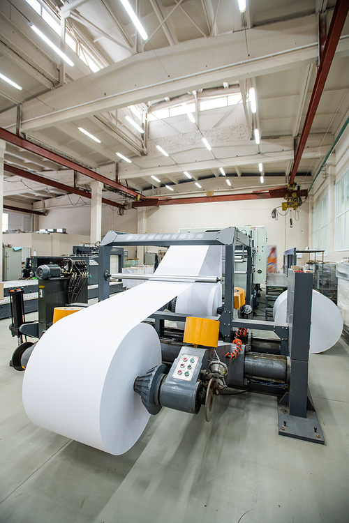 Automated printing press with white paper roll in industrial shop