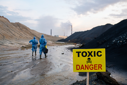 Announcement about toxic and dangerous area on background of two contemporary female scientists in blue protective coveralls