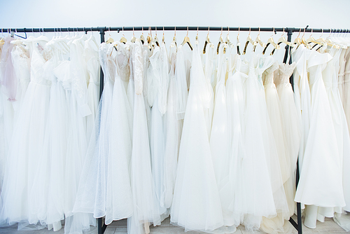 Horizontal no people shot of beautiful wedding dresses on clothes rails in modern bridal dress-making studio