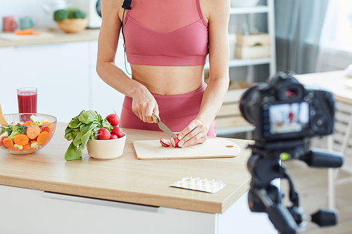 Close up of unrecognizable fir woman cutting radish while recording video on healthy food, copy space