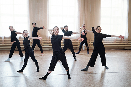 Horizontal shot of professional young dancers wearing black outfits reahearsing their new dance in studio