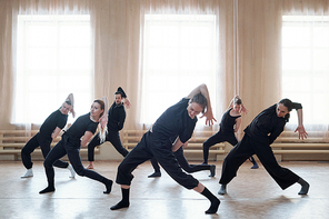 Team of contemporary dancers working on new dance moves together in their rehearsal studio, horizontal shot