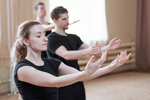 Horizontal portrait of young contemporary dancers wearing black clothes learning new dance move together