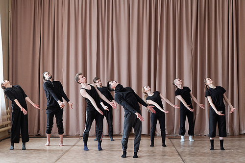 Horizontal shot of professional dancers wearing black outfit rehearsing their new contemporary dance