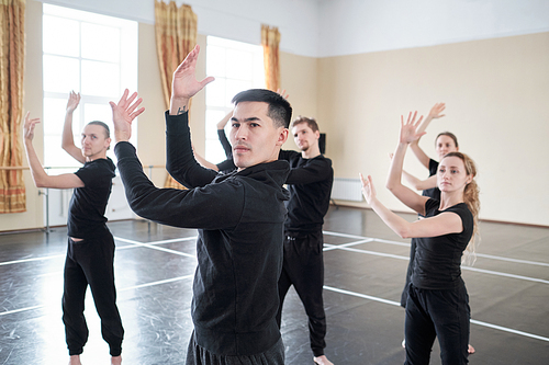 Young man and women wearing black clothes rehearsing their new contemporary dance moves
