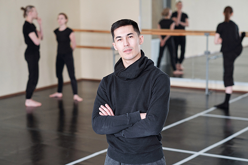 young confident instructor of modern dance dancing course crossing arms by chest while standing in front of camera in studio
