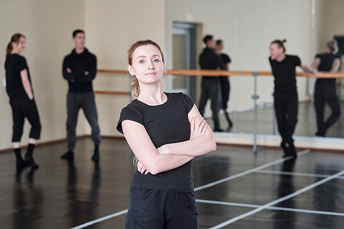 Horizontal medium portrait of Caucasian woman wearing black outfit standing with arms crossed in dance studio