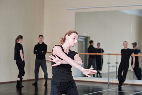 Horizontal medium portrait of beautiful young woman wearing black clothes dancing in rehearsal studio