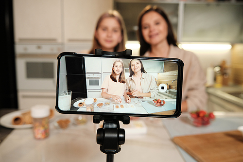 Smartphone screen during livestream of home cooking masterclass where two young females preparing homemade icecream in the kitchen