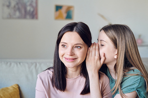 Teenage girl whispering gossips in mothers ear while sharing her secret, privacy concept