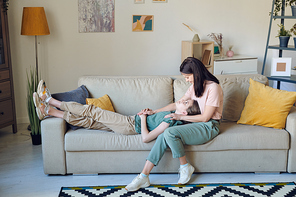 Teenage girl lying on mothers knees and sharing news with her while they spending time at home