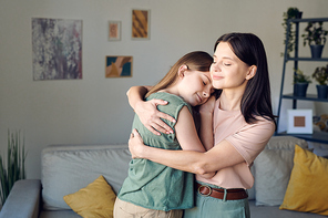 young loving mother embracing her cute affectionate daughter in home  after coming back from business travel or work