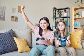 Excited mother winning video game while her distraught daughter looking with sadness at monitor