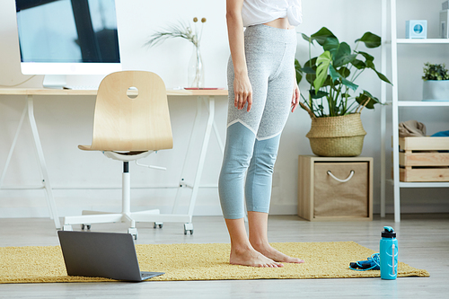 Low section view at unrecognizable woman standing on carpet at home ready for online work out, copy space