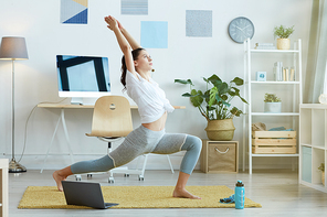 Full length portrait of contemporary young woman doing yoga exercises during fitness workout at home, copy space