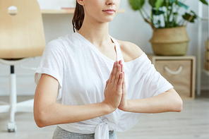 Cropped portrait of contemporary young woman doing yoga at home while sitting in lotus position, copy space