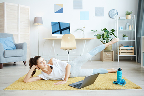 Full length portrait of smiling young woman enjoying home workout online via laptop, copy space