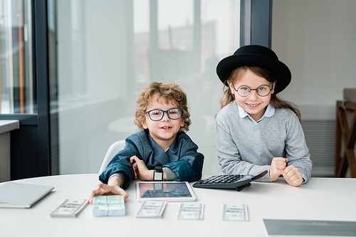 Two cute little accountants looking at you while counting and giving you salary in front of camera in office